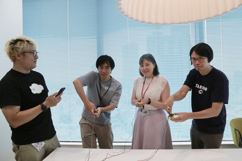 ボタンを構える3人と、出題者の4人が写った写真