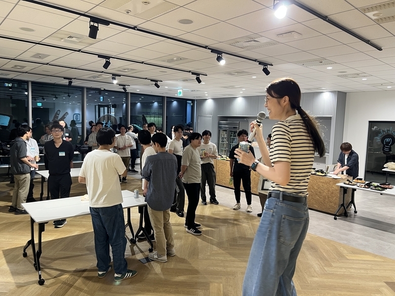 乾杯の音頭を取るeminemさんと、その奥に乾杯を心待ちにするSmartHRメンバーたちが居ます