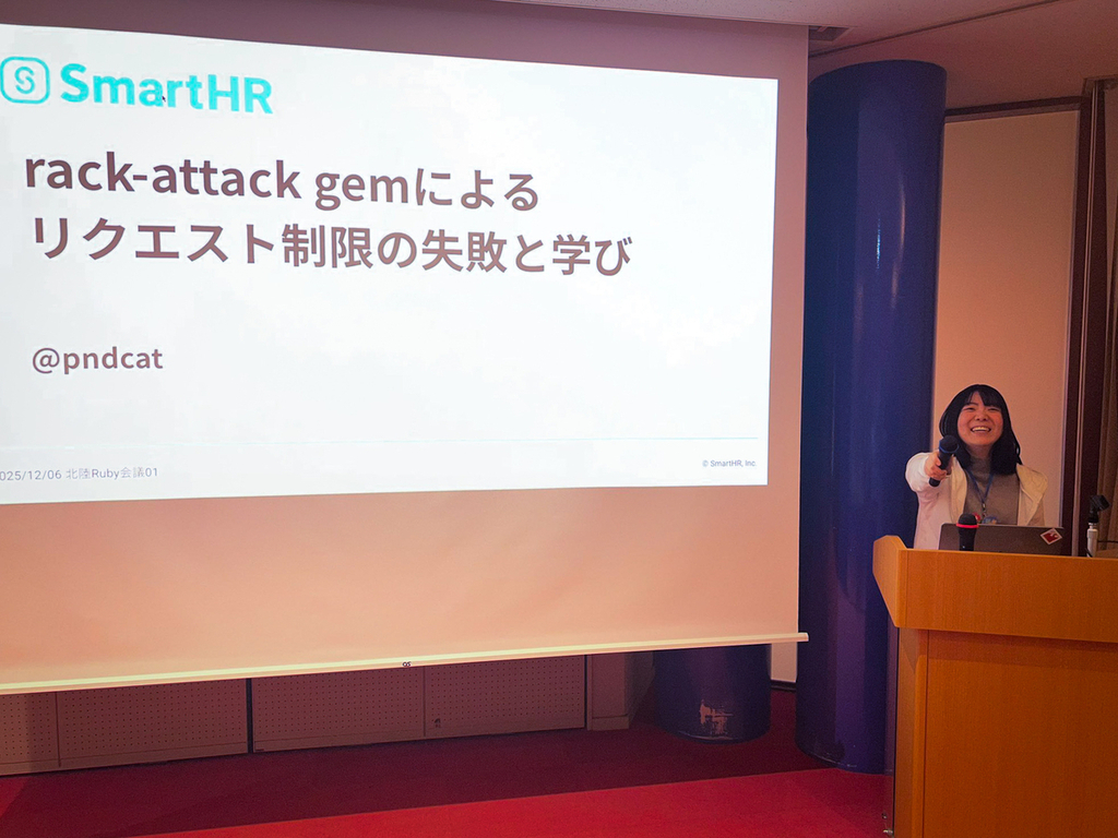 スクリーンの横でマイクをこちらに向けて、笑顔で写っている