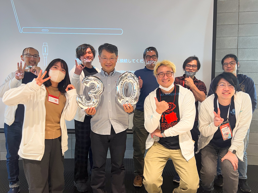 集合写真。手前に4名、奥に5名写っていて、手前の左から二人目の方が30の形の風船を持っている