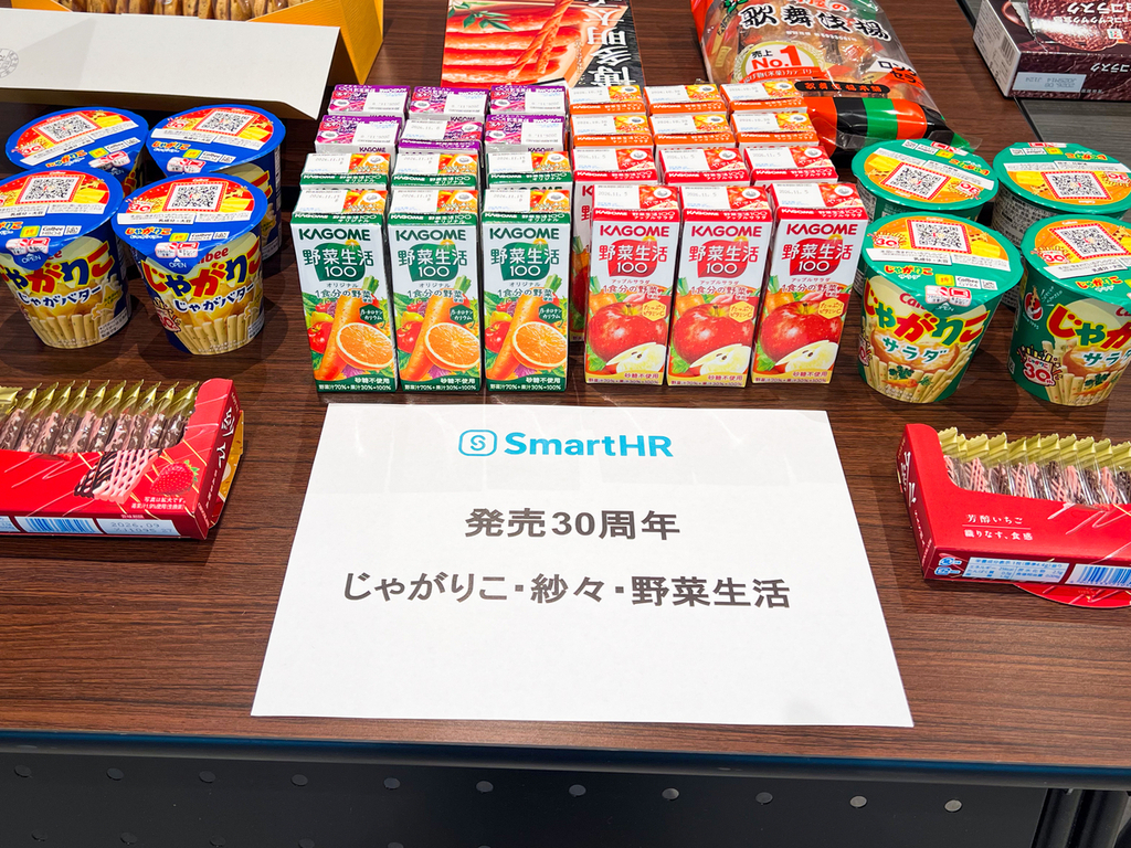 手前に紗々と発売30周年、じゃがりこ・紗々・野菜生活と書かれた紙、奥にはじゃがバター味のじゃがりこ、野菜生活のパックジュース、サラダ味のじゃがりこが置かれている
