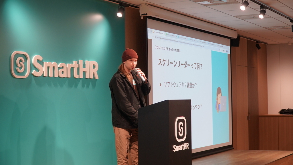 マイクを持ち会場へ問いかけている男性の写真