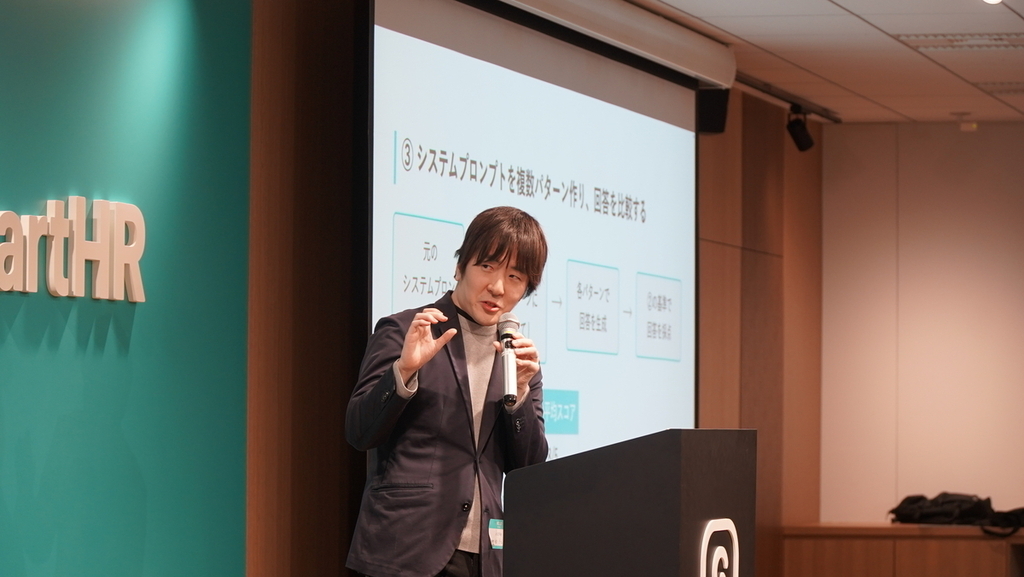 マイクを片手にスライドの内容を語る男性の写真
