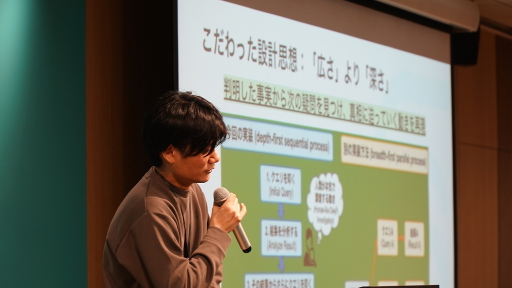スライドパネルを背中に語る男性の写真