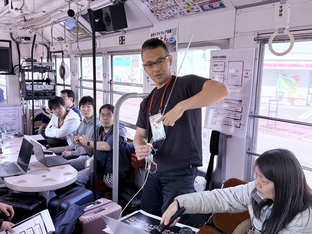 棒状の自作楽器を演奏しながら発表している登壇者