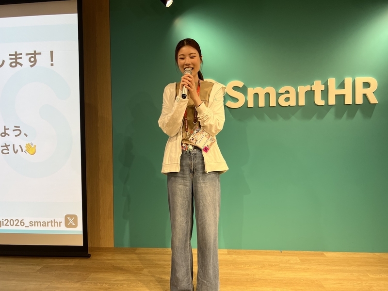 ステージ上のSmartHRバックパネルの前に立ち、マイクを持ってイベントの締めの挨拶をするeminemさん