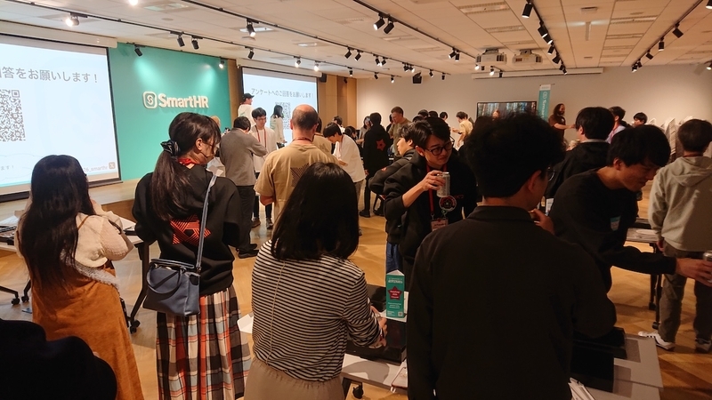 明るい会場内にたくさんの参加者が集まり、お酒やフードを片手に笑顔で賑やかに談笑し合っている、活気あふれる懇親会の全体風景