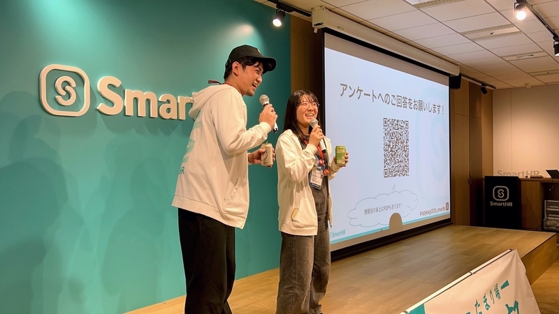 LT大会が終了し、ステージの上で並んでマイクを持ち、ドリンク缶を高く掲げて笑顔で懇親会の乾杯の音頭を取るosyoyuさんとpndcatさん