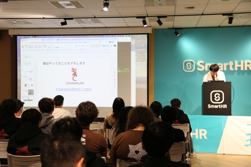 「The Box Garden Struggles Since 2016~」というスライドの横に立ち、マイクを片手に、開発中のOSS「Vivarium」の仕組みやデモについて熱弁するudzuraさん