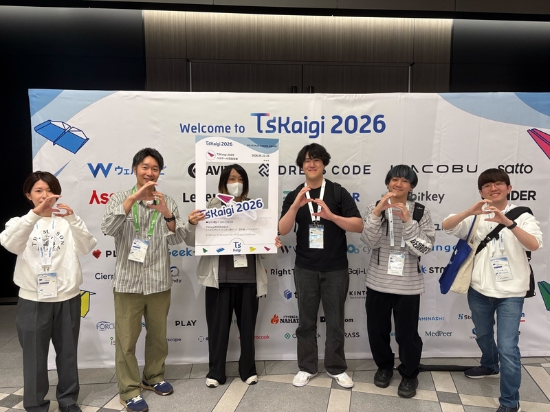 TSKaigi 2026のスポンサーパネルの前で6名の男女が手をSの形にしている