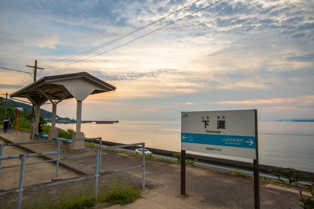 秋の夕暮れ時に美しい伊予灘と海が広がる愛媛県のJR下灘駅ホームと駅名標