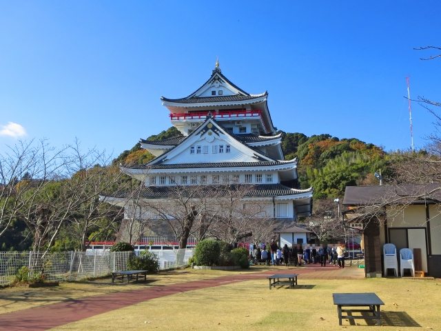 青空の下にそびえ立つ熱海城の天守閣と庭園の景色。シニアの熱海観光や旅行の定番スポット