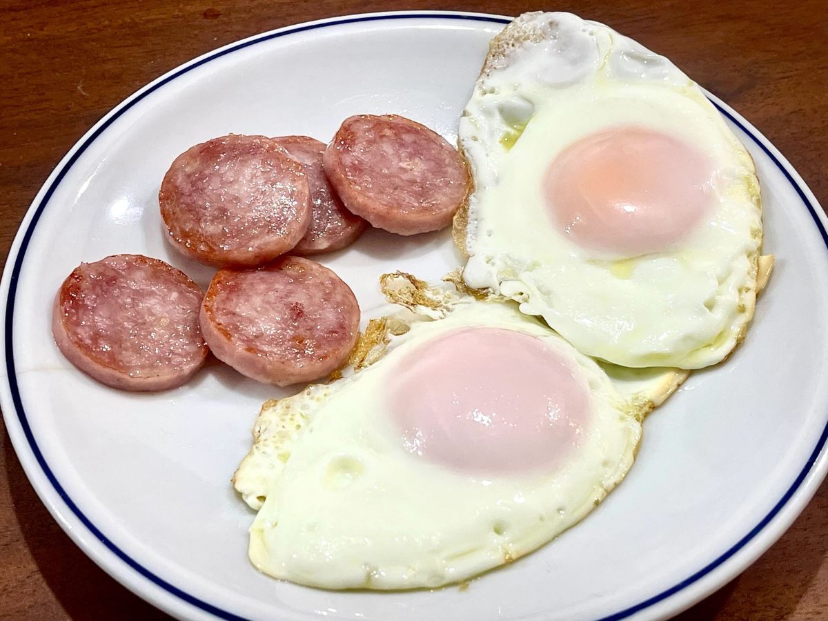 長崎雲仙ハム ポークソーセージ（ボロニア）を焼いたものと目玉焼きが皿の上に並んでいる
