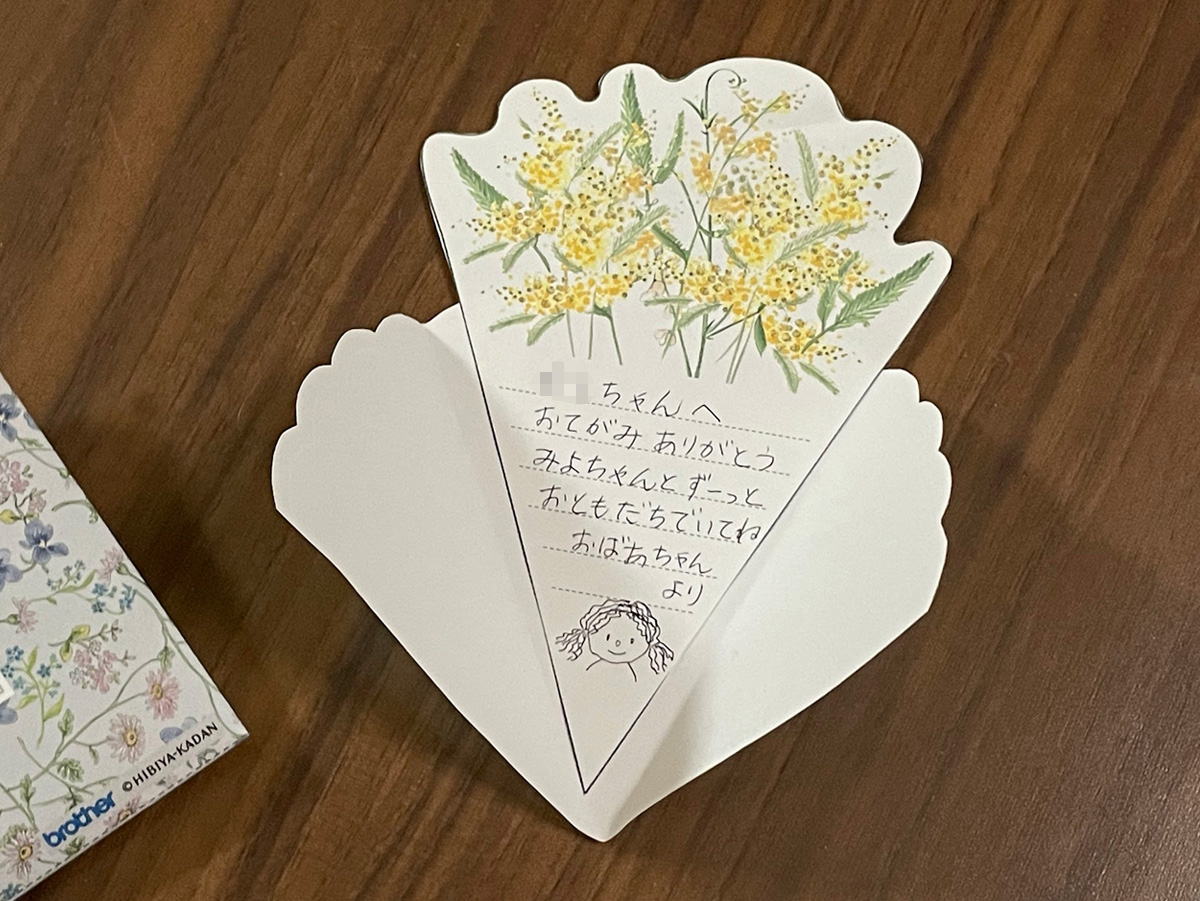 花束カードに書かれたおばあちゃんからのお返事。お人形の「みよちゃん」の似顔絵も描いてある