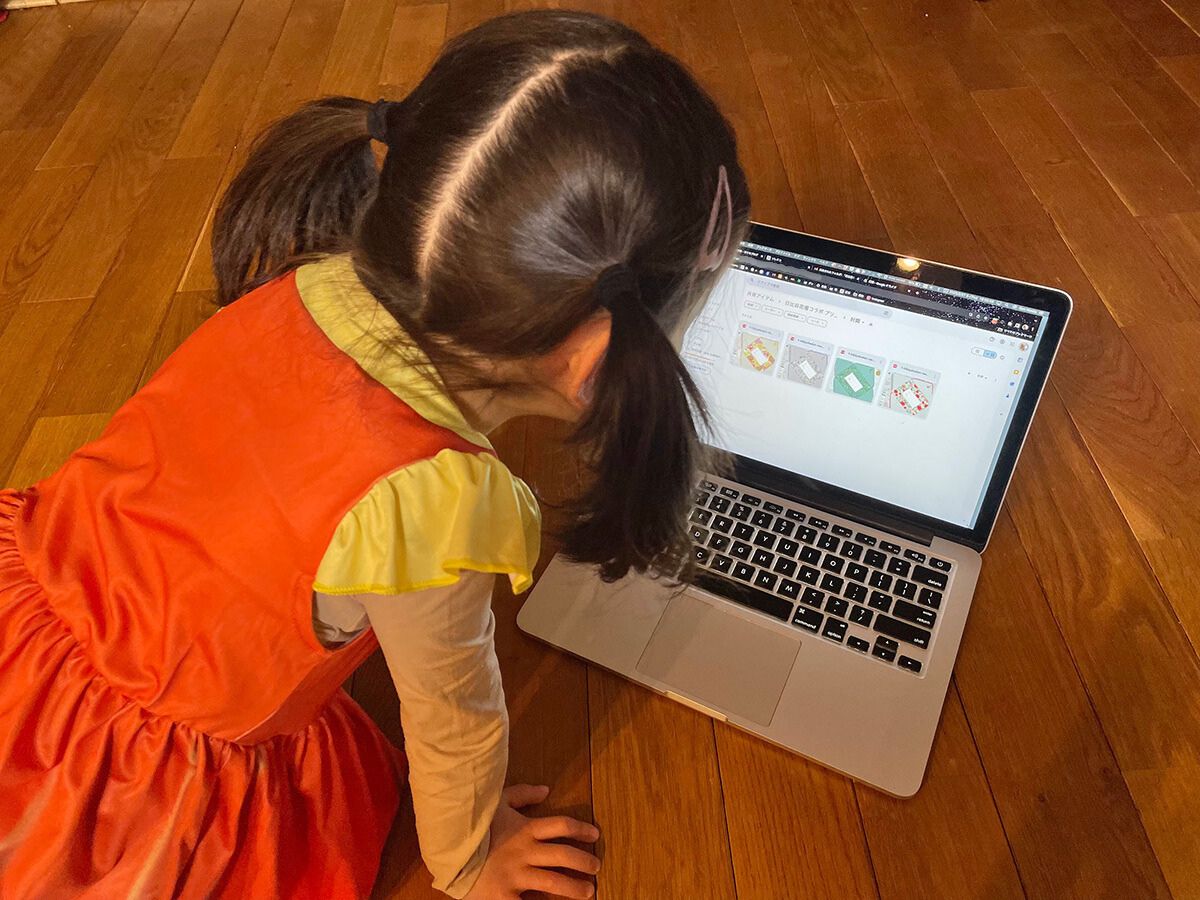 封筒のデザインが表示されたパソコン画面を真剣な表情で覗き込む娘