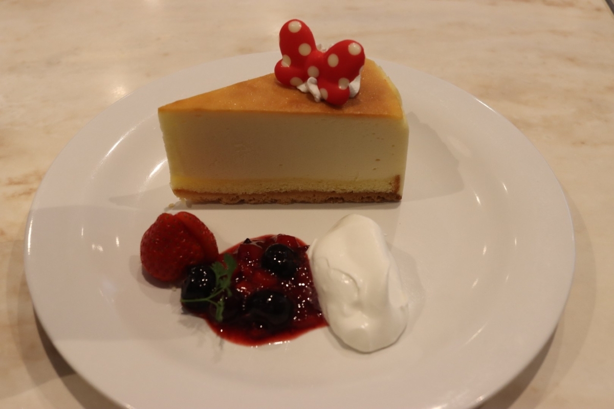 チーズケーキの写真。ミニーのリボンとベリーソースが添えられている