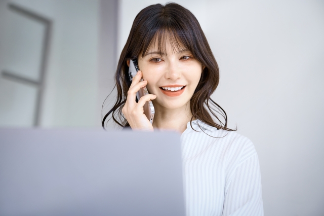 投資スクールのオンライン勉強中にパソコンを目の前に置いて通話で質問している女性