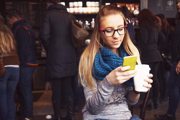 Girl sitting in cafe, texting message and drinking coffee.