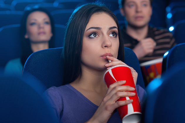 Watching an exciting movie. Attractive young woman drinking soda while watching movie at the cinema