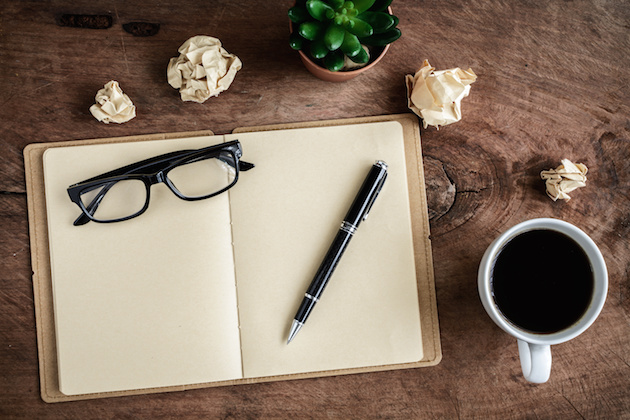 Cup of coffee with notebook on old wooden desk