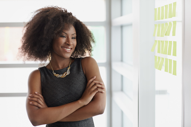 Portrait of a smiling business woman with an afro in bright glass office