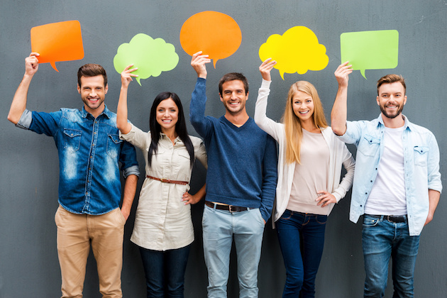 Global communications. Group of happy young people holding empty speech bubbles and looking at camera while standing against grey background