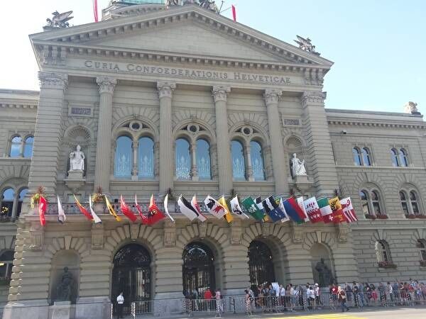 スイス連邦議会議事堂正面。国旗のほか、各州の旗が飾られている。見学者が列を作っている。