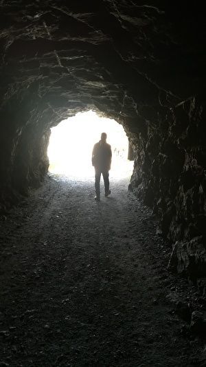 トンネルの向こうに外に光が見える。光の中に男性が立っている影が見える。