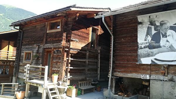 伝統的なスイスのシャレーが並んでいる。木の壁にラクレットを調理する人の白黒の写真が飾られている。