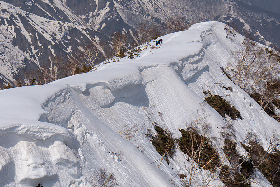 雪庇の尾根をゆく人々