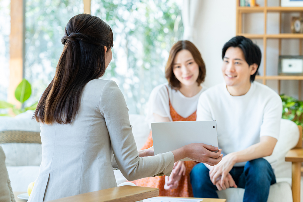 タブレットで若い夫婦に説明するビジネスウーマン