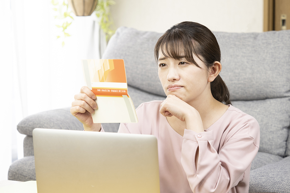 預金通帳を見て悩む女性