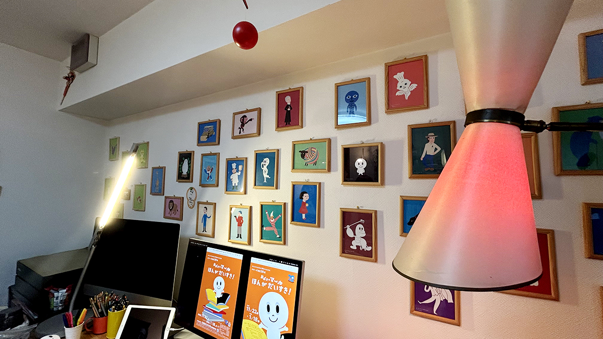 取材を見守る壁いっぱいのキャラクターたち。あっ、デスクトップにマール20年展のビジュアルが！