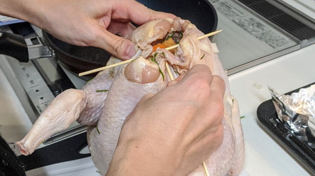 丸鶏のおしりを閉じているところ 丸どりのおしりを竹串で閉じている写真