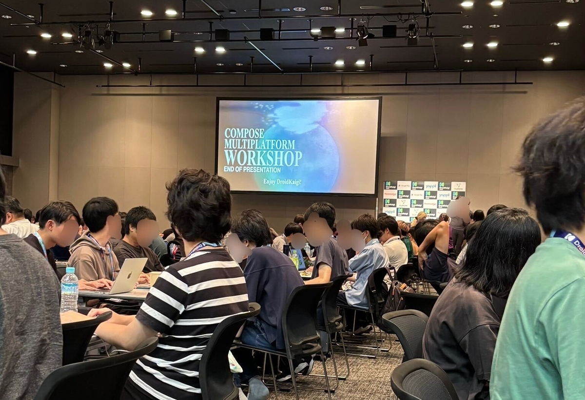 ワークショップの様子 スクリーンにワークショップのタイトルがあり、大勢の参加者が座っている