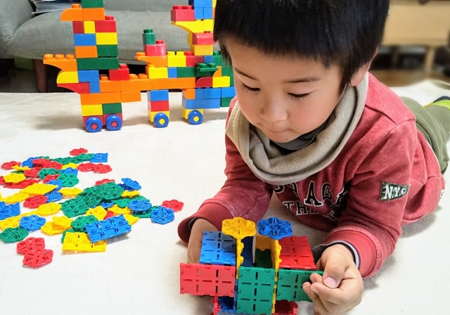 寝転がってブロックで遊ぶ男の子