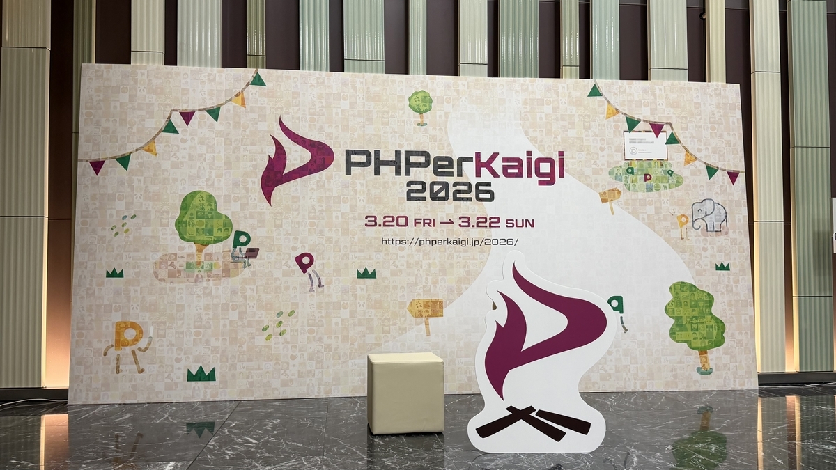 PHPerKaigi 2026の会場の撮影スポット。ロゴ入りの大きなパネルが背景になっている。