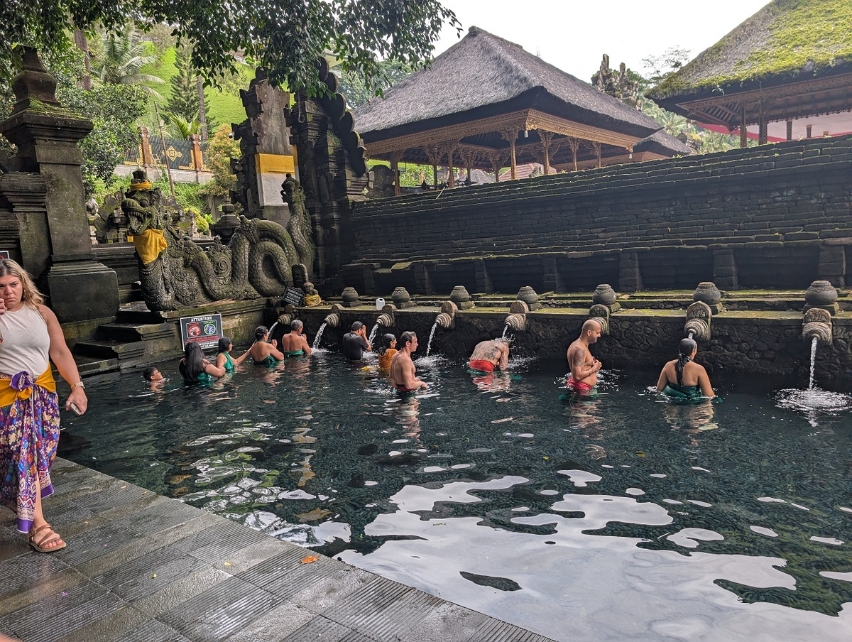 ティルタ・ウンプル寺院の沐浴場で霊水を浴びる人々