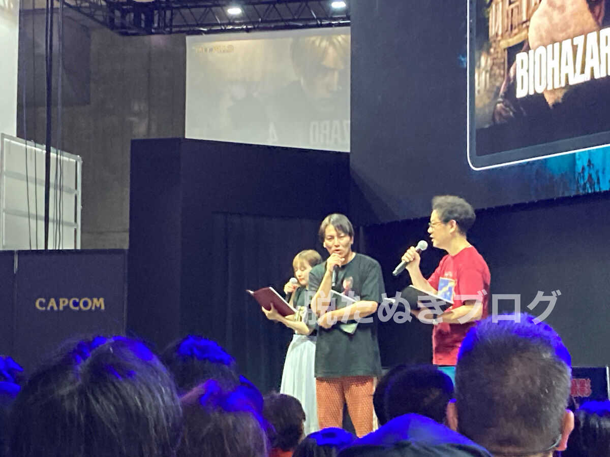 ゲームイベントのステージ上で、芸能人がゲームをプレイしている様子。CAPCOMブースでは狩野英孝さんがバイオハザードを試遊中。