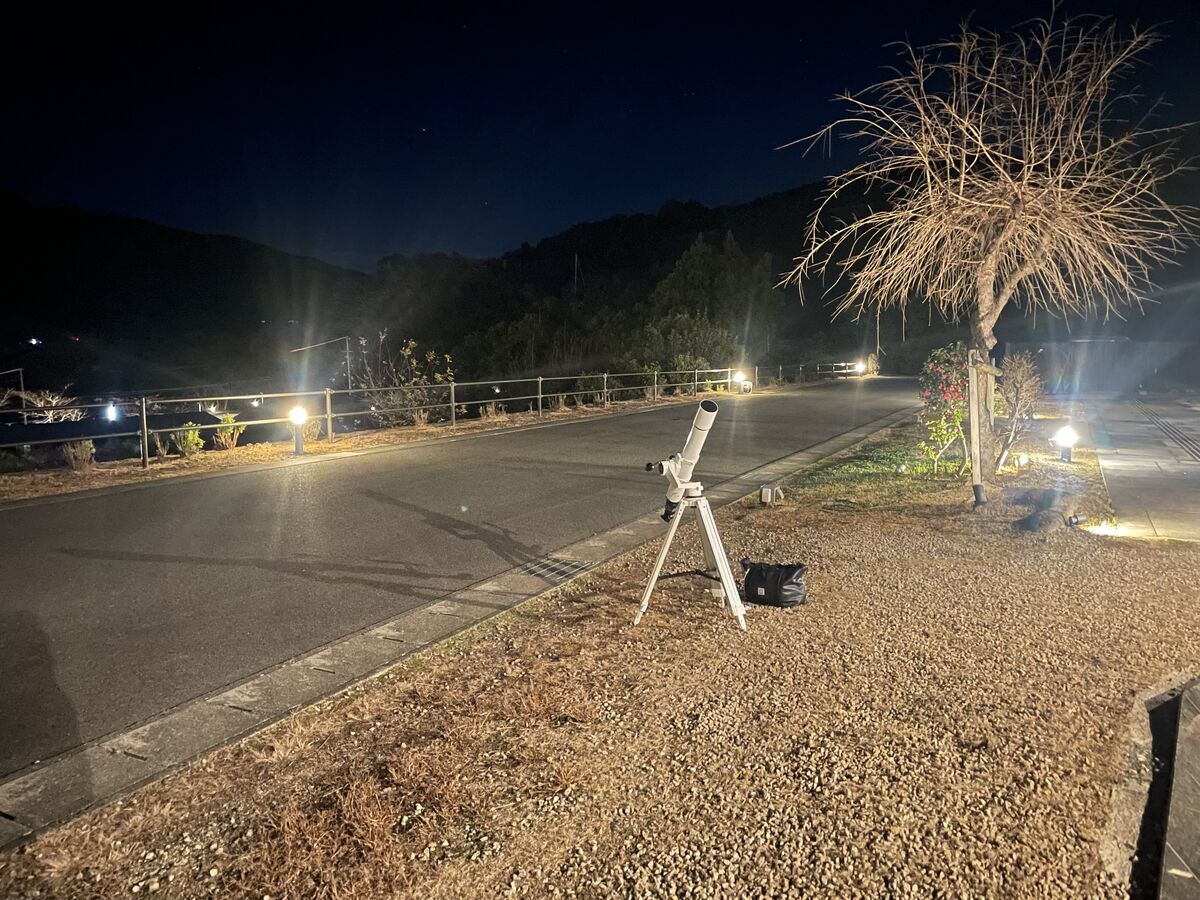 夜のラウンジ外に集まる人々と天体望遠鏡。星空観察の様子。