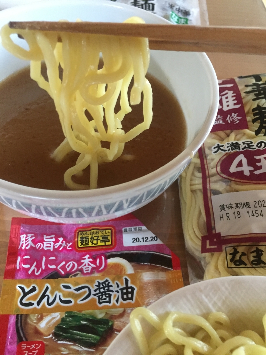 極太麺にとんこつ醤油を絡めて食べる様子を撮影した写真