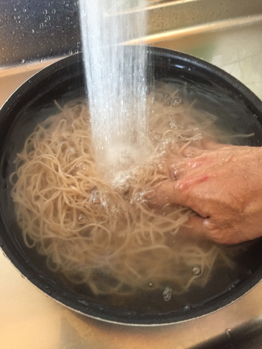 町田市根岸町にあるスーパー三和「アメリア三和町田根岸店」で購入したおびなた社の「生八割蕎麦」を茹で上げて、流水で滑りを洗い流している写真