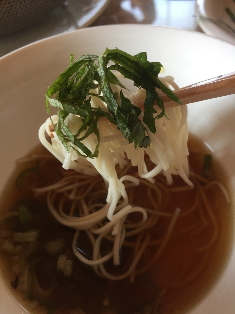 ざるそばの食べ方の紹介として刻んだシソの葉と一緒にざるそばをめんつゆに絡めて撮影した写真
