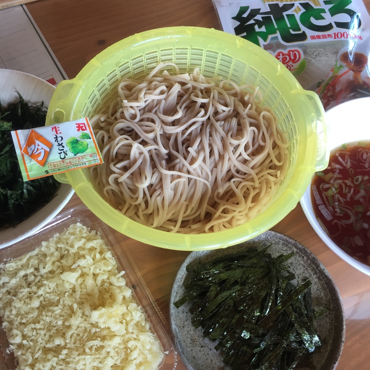 ざるそばの食べ方の紹介としてたくさんの様々な具材と一緒に乾麺のそばを中心に置いて撮影した写真