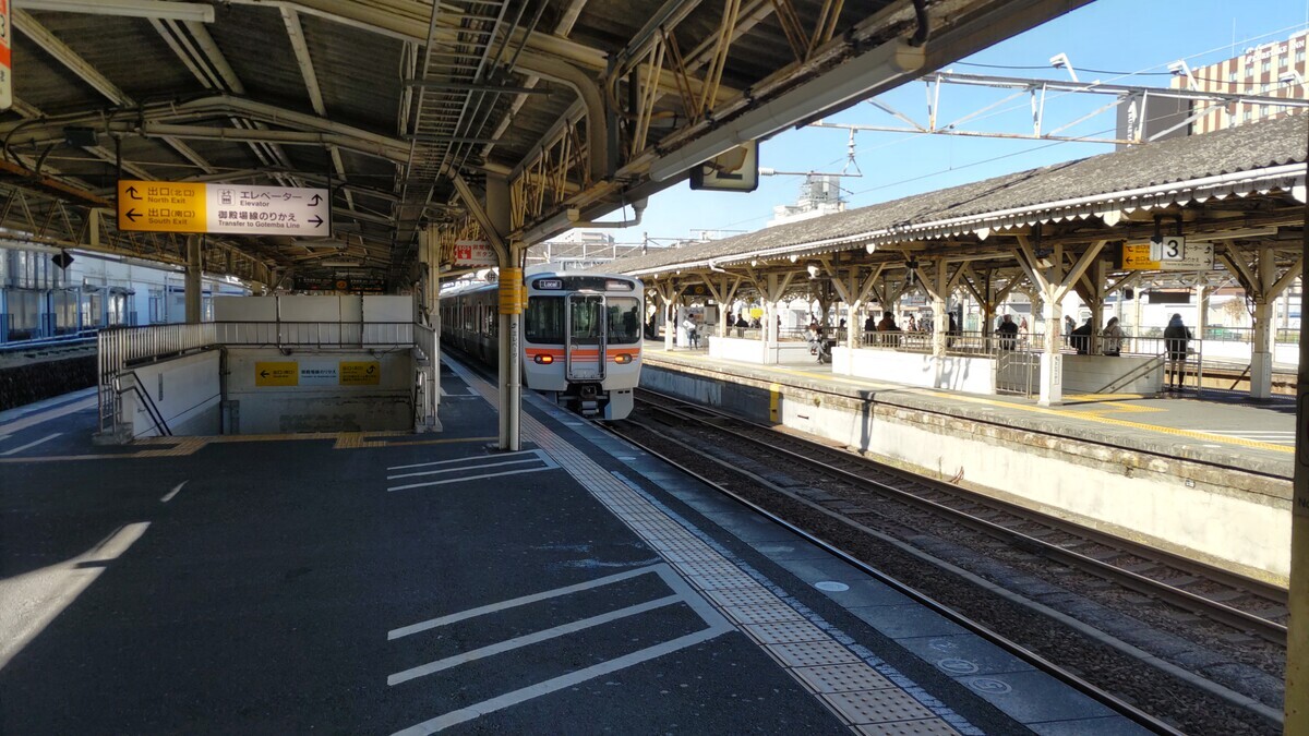 沼津駅のプラットフォームの風景。右側のホームから電車が画面奥へ走っていく。快晴。