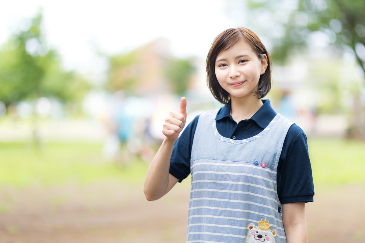 サムズアップポーズをとるエプロン女子