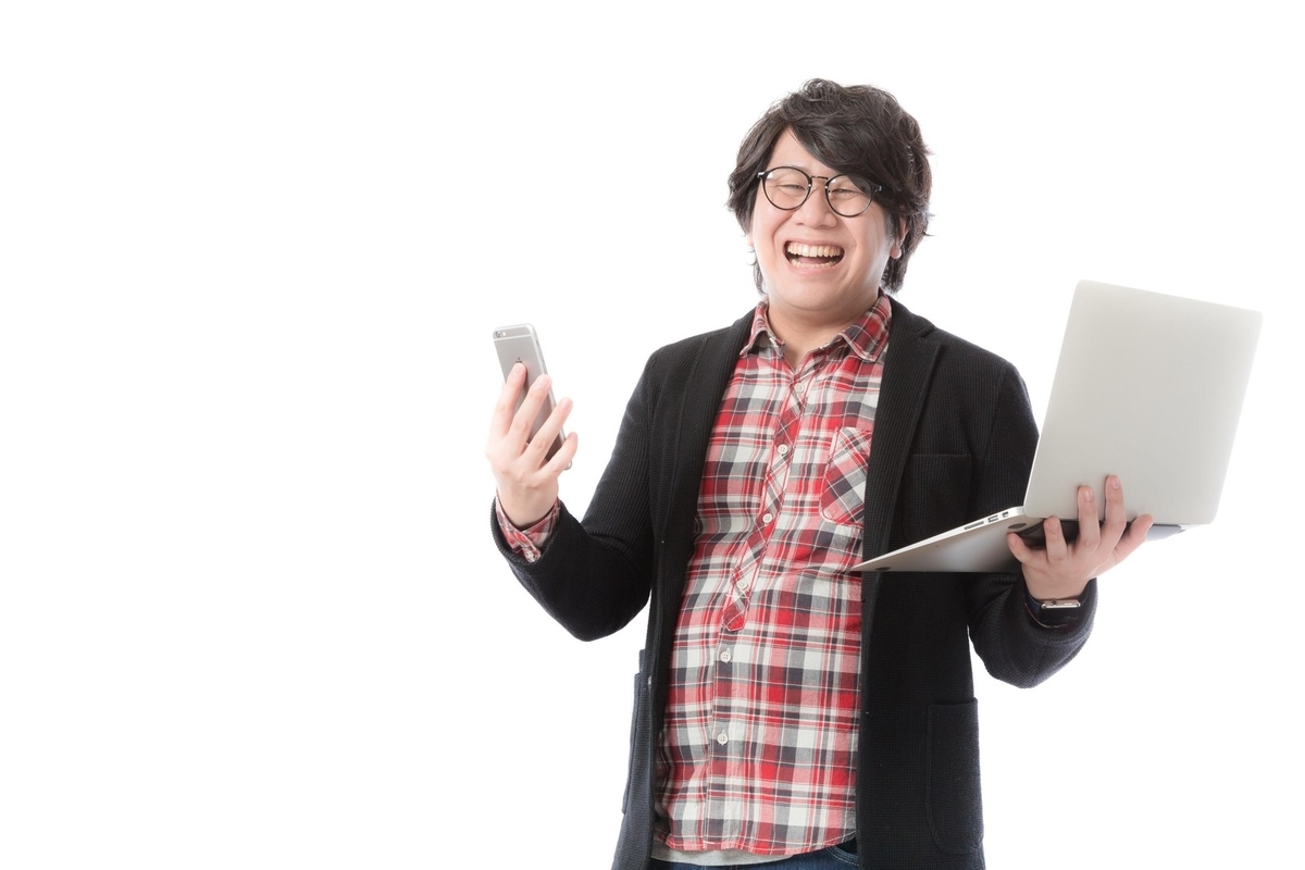 パソコン、携帯を持って楽しそうに仕事をしている男性
