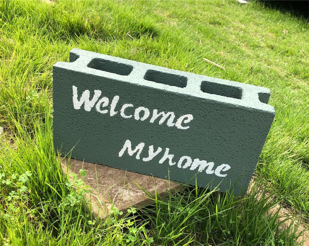 Wellcome Myhomeと書かれたコンクリートブロック。無塗装のコンクリートブロックの上に置いて飾った図。グリーンの芝生の上。