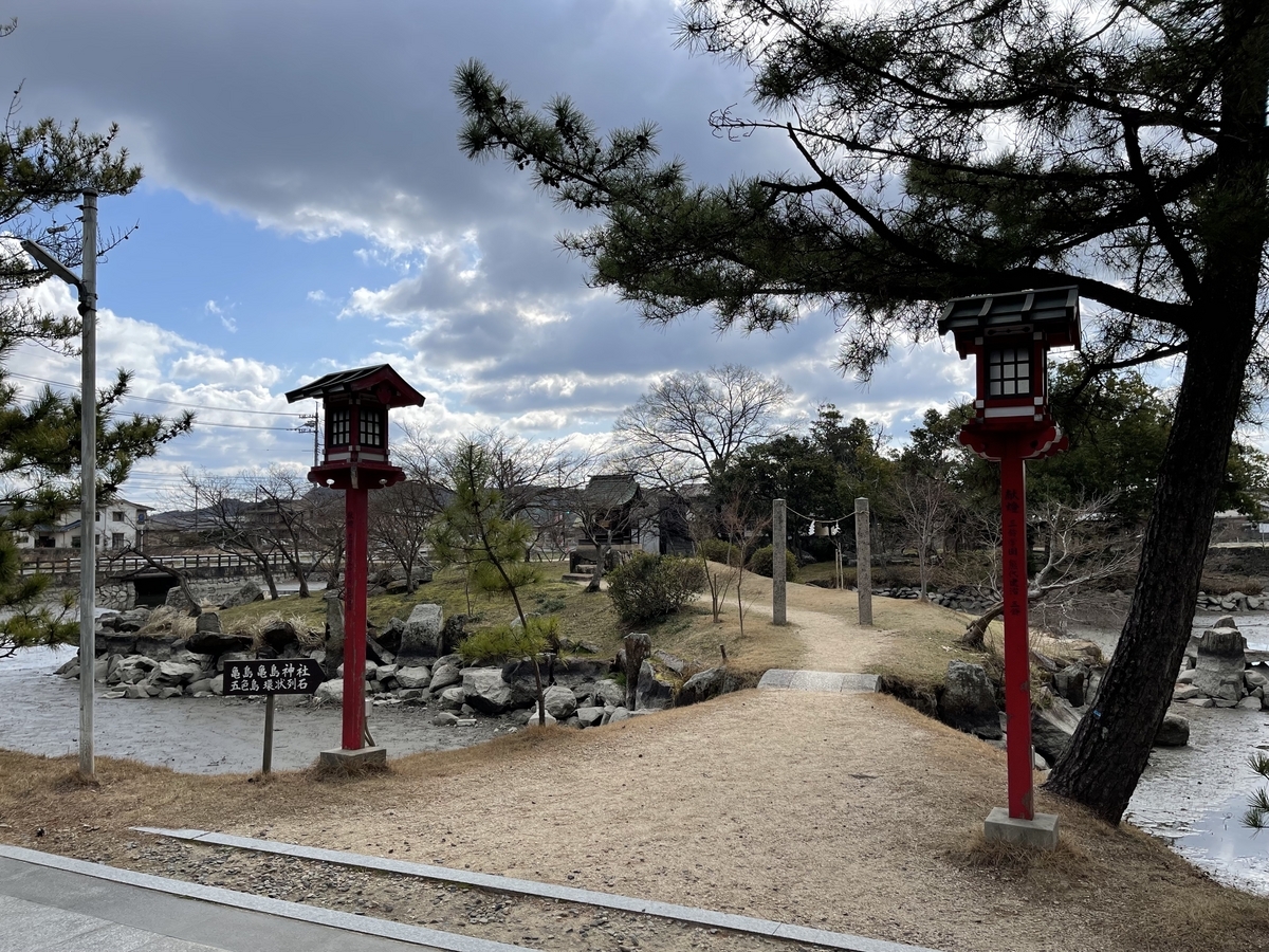 池の左側の小島である亀島を参道から撮った写真です。渡り道の両脇には赤い灯籠が立っています。