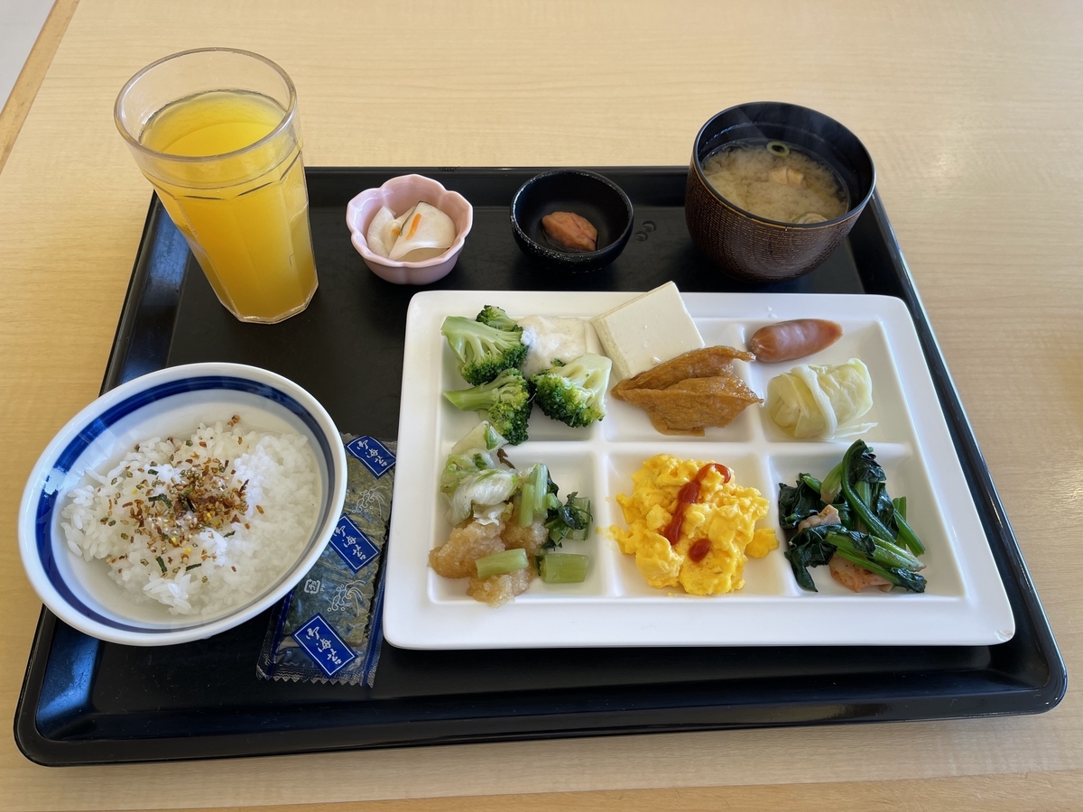 左手前にご飯、右手前におかず、左奥にオレンジジュース、右奥にお味噌汁などを置いています。